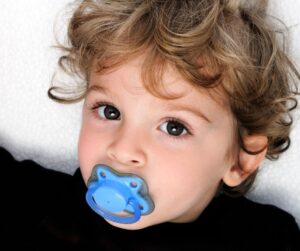 picture of a toddler with a blue pacifier in their mouth